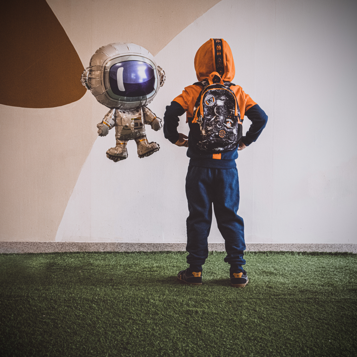 dziecko w ubraniach i obuwiu Bejo wpatrujące się w balonik z astronautą