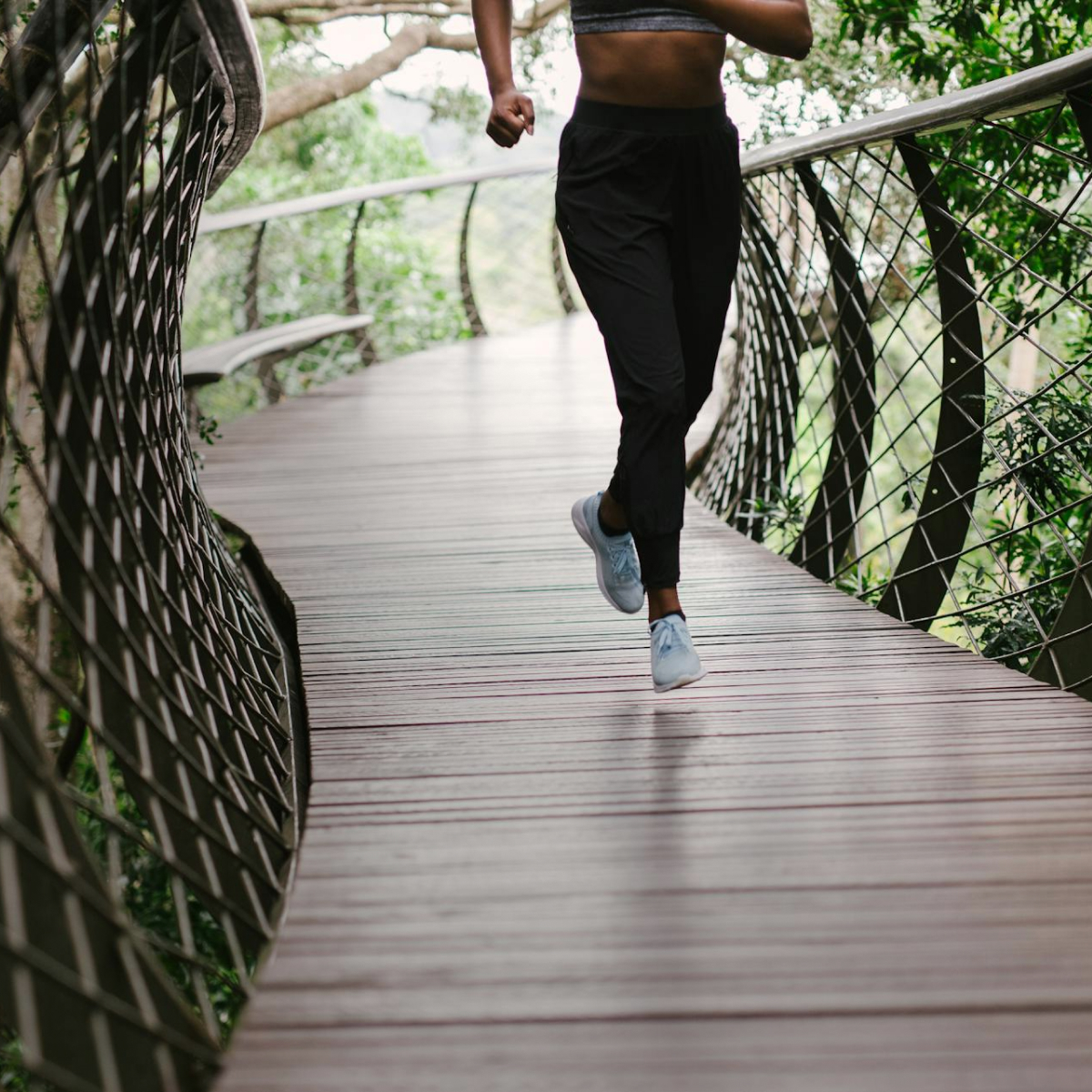 Žena bežiaca po moste v pohodlných bežeckých topánkach
